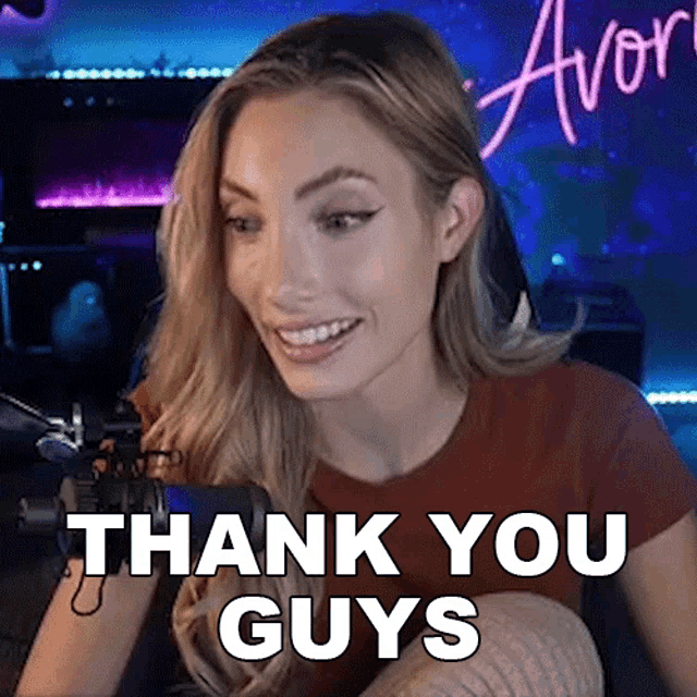 a woman is sitting in front of a microphone and smiling while saying thank you guys .