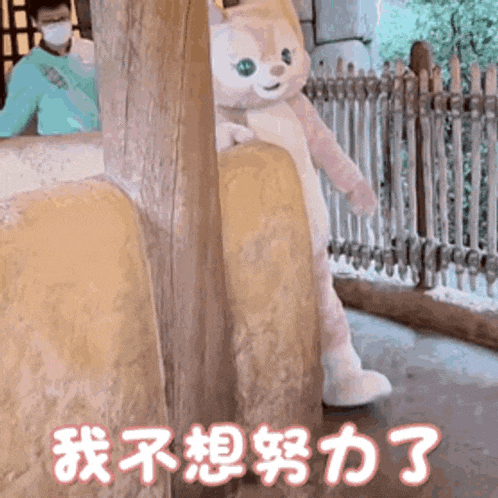 a stuffed animal is peeking out from behind a wall and a man in a mask is standing behind it .