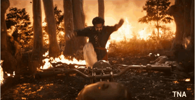 a man is riding a motorcycle in a forest with a tna watermark