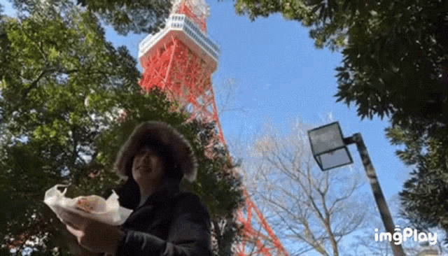 a person holding a bag of food in front of a red and white tower ..