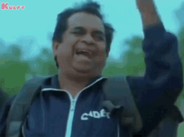 a man with a backpack is screaming and raising his fist in the air while wearing a blue jacket .