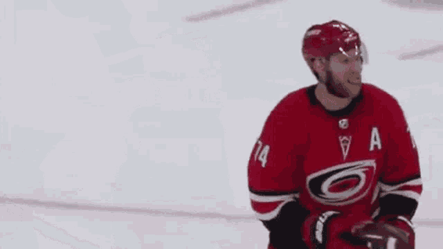 a hockey player is wearing a red and black jersey with a storm on it .