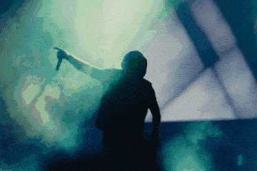 a silhouette of a man holding a microphone in a dark room