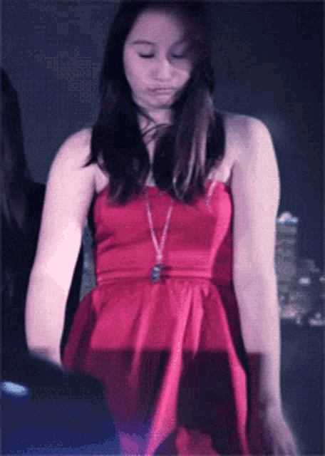 a woman in a red dress is standing in a dark room