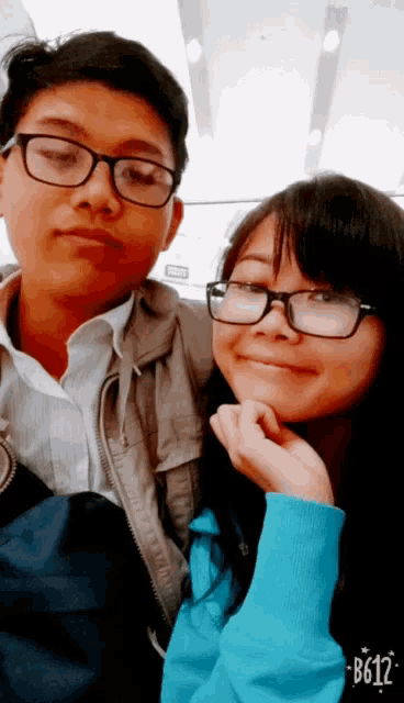 a boy and a girl are posing for a picture and the girl has glasses