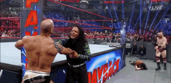two wrestlers are fighting in a wrestling ring with a sign that says wwe on it