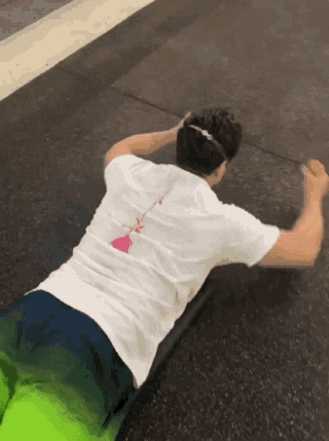 a man wearing a white shirt with a pink heart on the back is laying on the ground