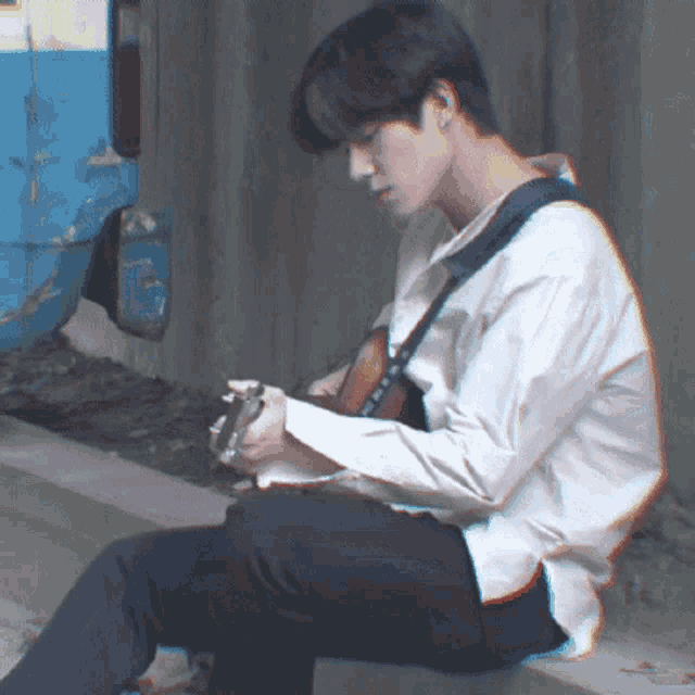 a man in a white shirt playing a guitar