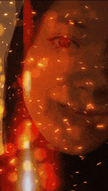 a close up of a woman 's face with sparks in the background