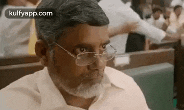 a man wearing glasses and a beard is sitting in a restaurant .