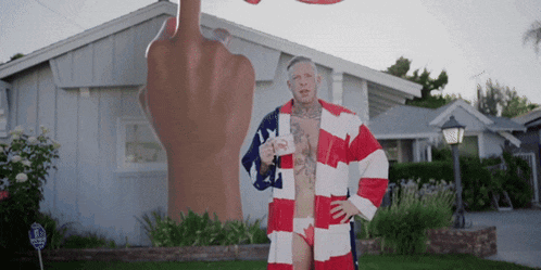 a man in an american flag robe is standing in front of a giant middle finger