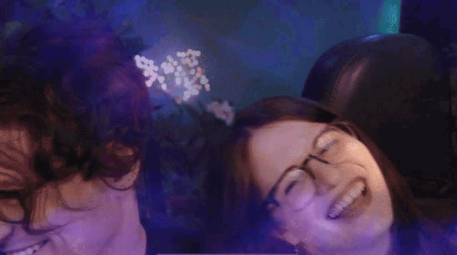 a man and a woman wearing glasses are smiling in a dark room