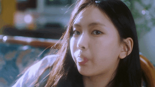 a close up of a young woman blowing bubble gum