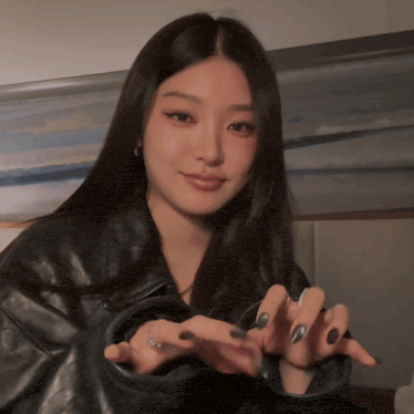 a woman wearing a black leather jacket with black nails