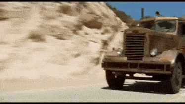 a large truck is driving down a dirt road .