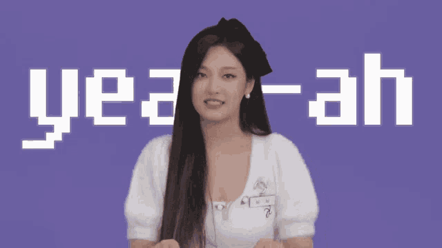 a woman is standing in front of a purple background that says ye-ah