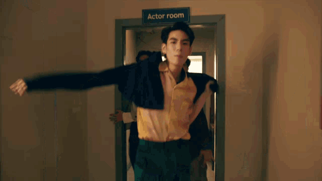 a man in a yellow shirt is being held by another man in the actor room