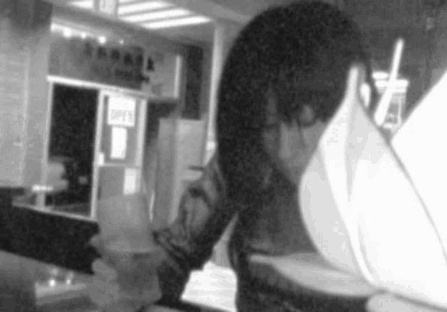 a black and white photo of a person looking at a menu in front of an open sign