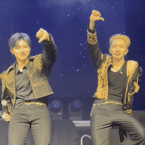 a couple of men standing on a stage with their arms up