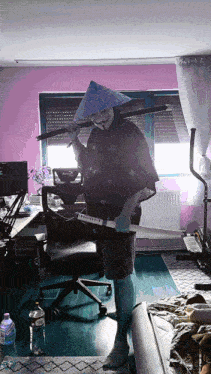a person wearing a conical hat and holding a sword in a room