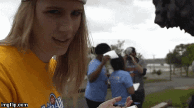 a woman wearing a yellow shirt with the word all on it smiles