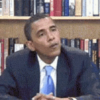 a man in a suit and tie is sitting in front of a book shelf