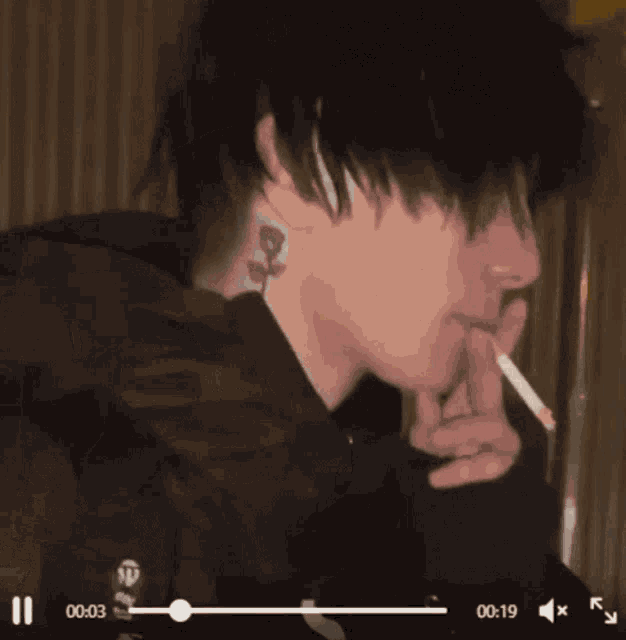 a man is smoking a cigarette in a dark room .