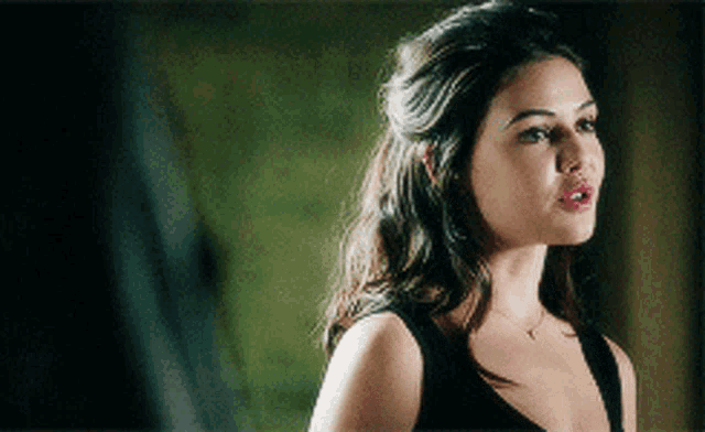 a woman in a black tank top with a necklace around her neck