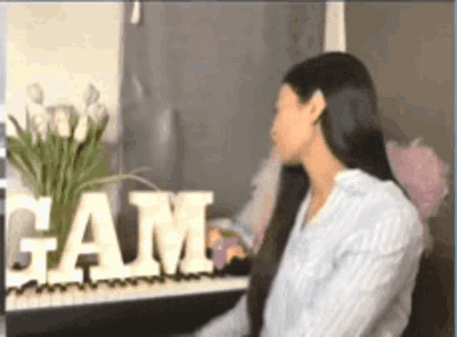 a woman is sitting at a piano in front of a sign that says ' gam ' on it .
