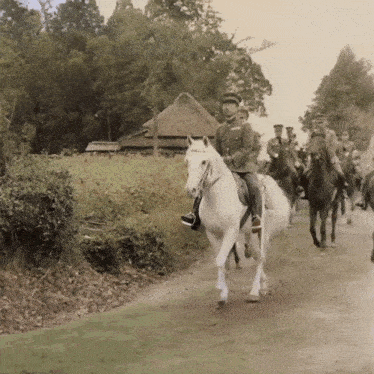 a group of men are riding horses down a path
