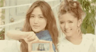 two young women are taking a picture of each other with their phones .