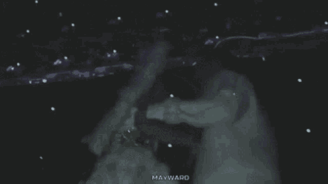 a person in a white dress is standing in the dark and the word mayward is on the bottom right