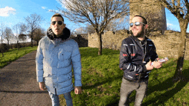 two men standing next to each other in a park