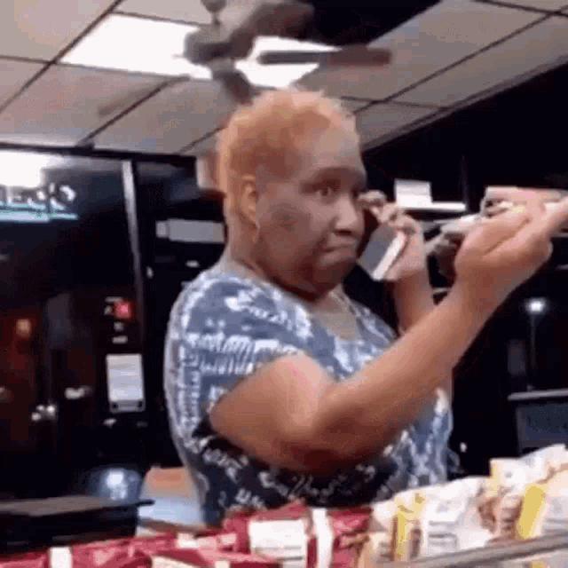 a woman is talking on a cell phone in a store while holding a bottle of soda .