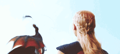 a woman in a braided ponytail holds a dragon in her arms