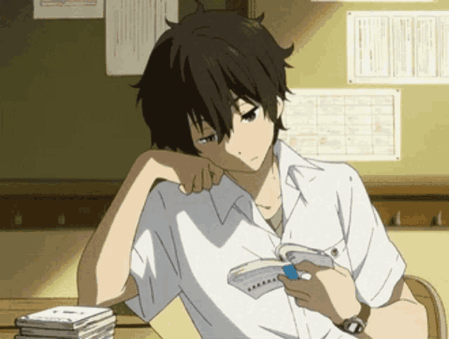a boy in a white shirt is sitting at a desk holding a book