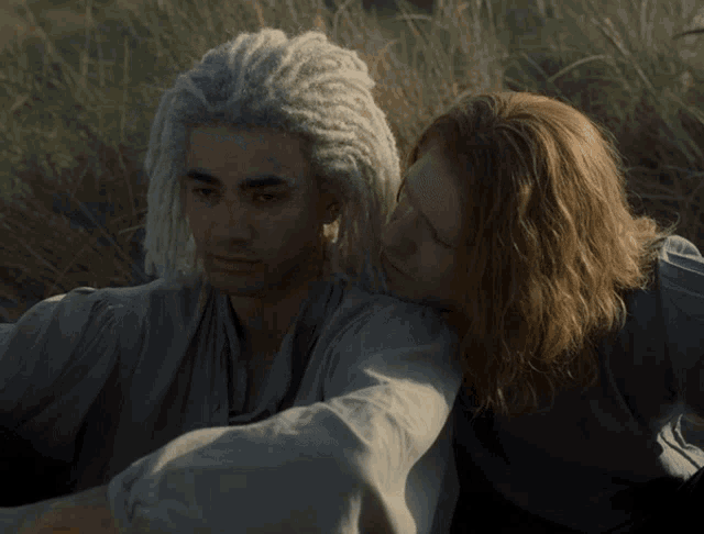 a man with dreadlocks sits next to a man with long red hair