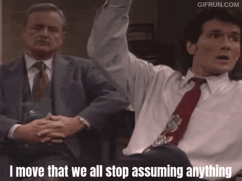 a man in a suit and tie is sitting next to another man and says i move that we all stop assuming anything