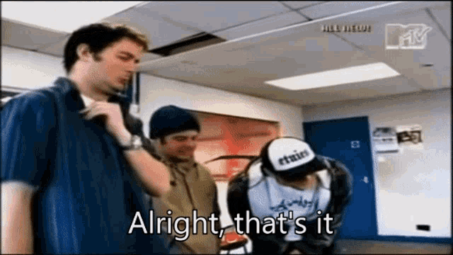 a group of men are standing in a room and one of them is wearing a hat that says etnies