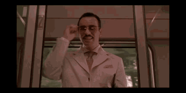 a man in a white suit and tie is smiling in a train