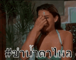 a woman in a bikini is covering her face with her hand while crying .