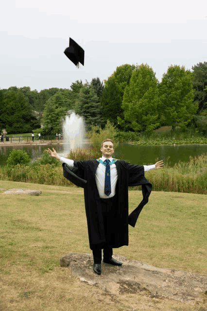 a man in a graduation gown is throwing his cap in the air