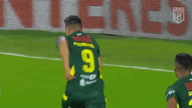 a soccer player wearing a green jersey with the number 9 on the back