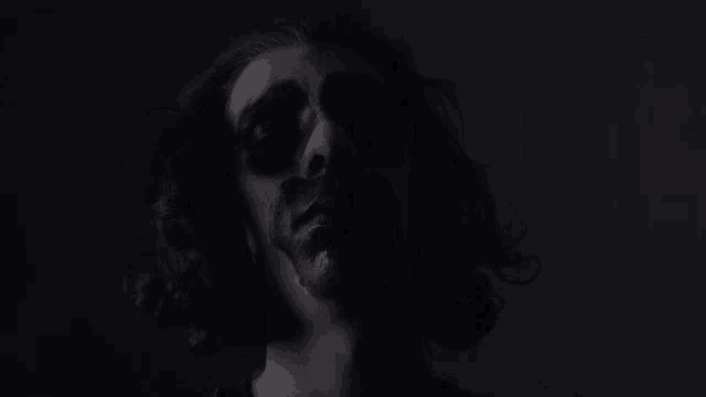a man with blood on his face is standing in the dark looking up at the camera .