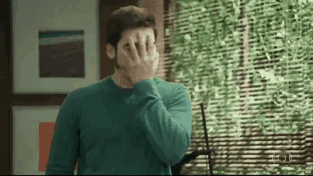 a man is covering his face with his hands in a living room .