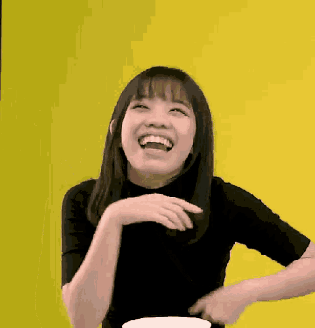 a young woman in a black shirt is laughing with her mouth open