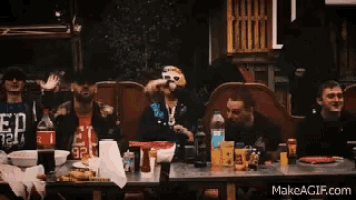 a group of people sitting at a table with a man wearing a shirt that says ed 32 on it
