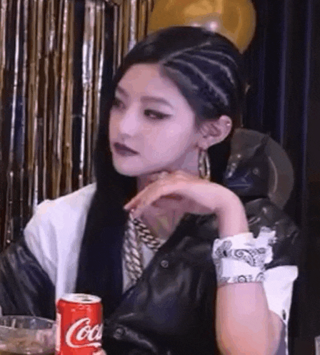 a woman is sitting at a table holding a can of coca-cola .