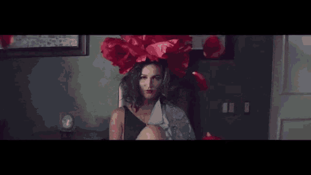 a woman with red flowers on her head is sitting in a room