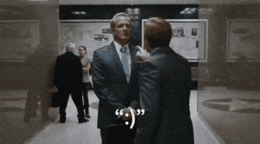a man in a suit and tie talks to another man